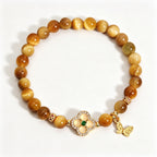 Earth Element golden tiger's eye bracelet, oriental five elements aesthetic women jewelry with four-leaf clover and butterfly pendant, plain white background e-commerce product shot