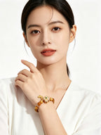 Upper body shot of woman in plain white outfit wearing Earth Element golden tiger's eye bracelet, only wrist jewelry, solid white background oriental fashion display