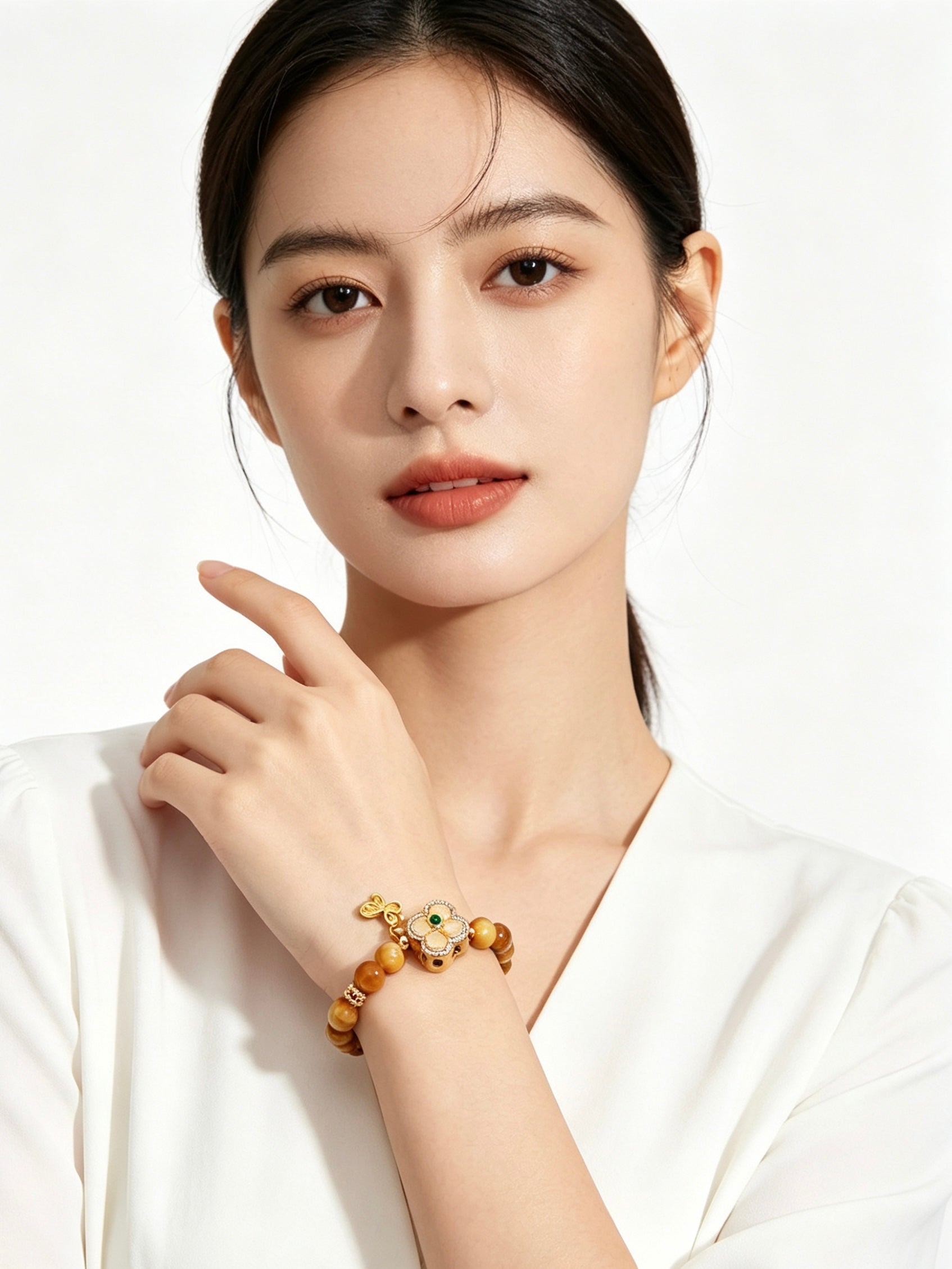 Upper body shot of woman in plain white outfit wearing Earth Element golden tiger's eye bracelet, only wrist jewelry, solid white background oriental fashion display