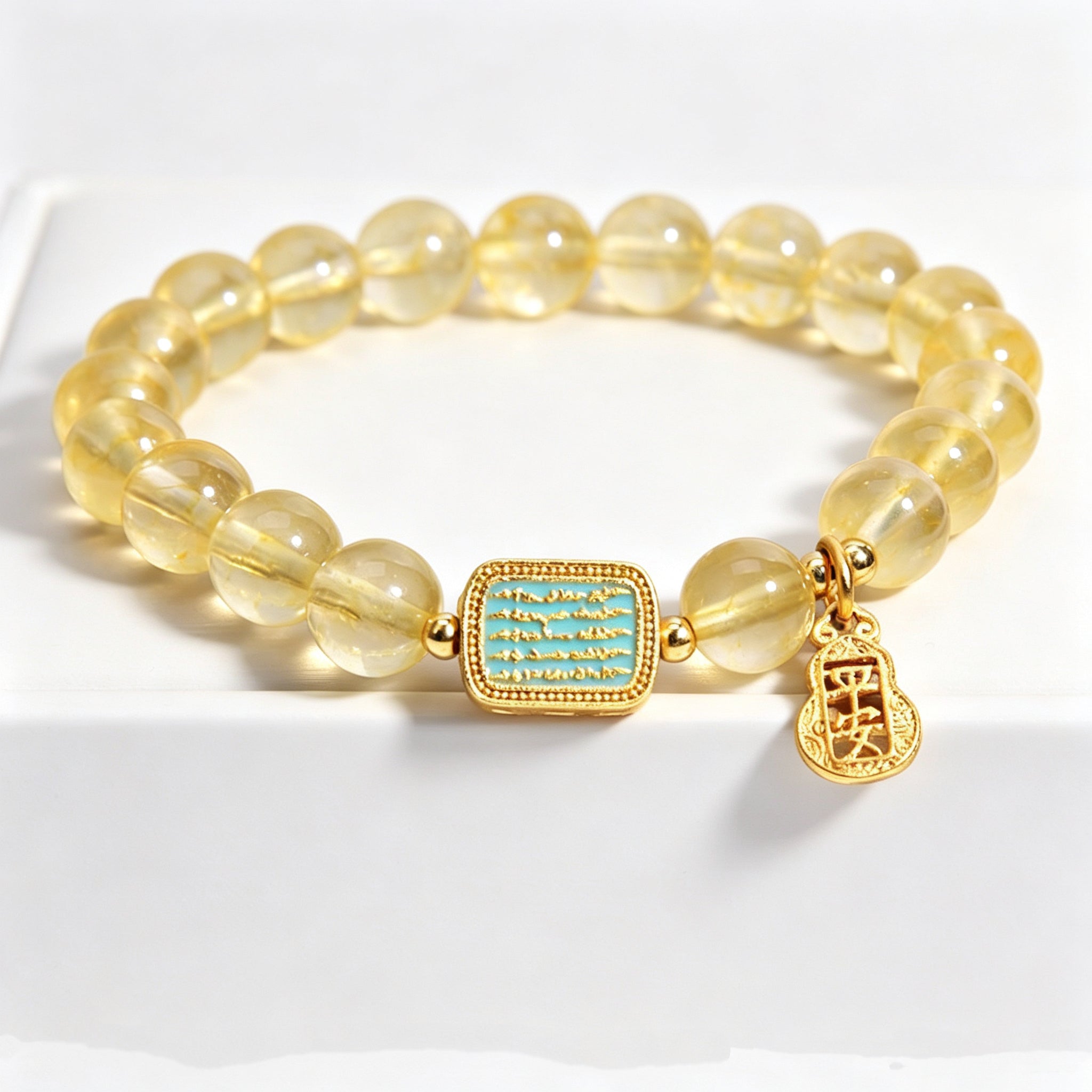 Close-up of hollow gold safe gourd "peace" pendant on metal element citrine bracelet, delicate vintage carving details against white background
