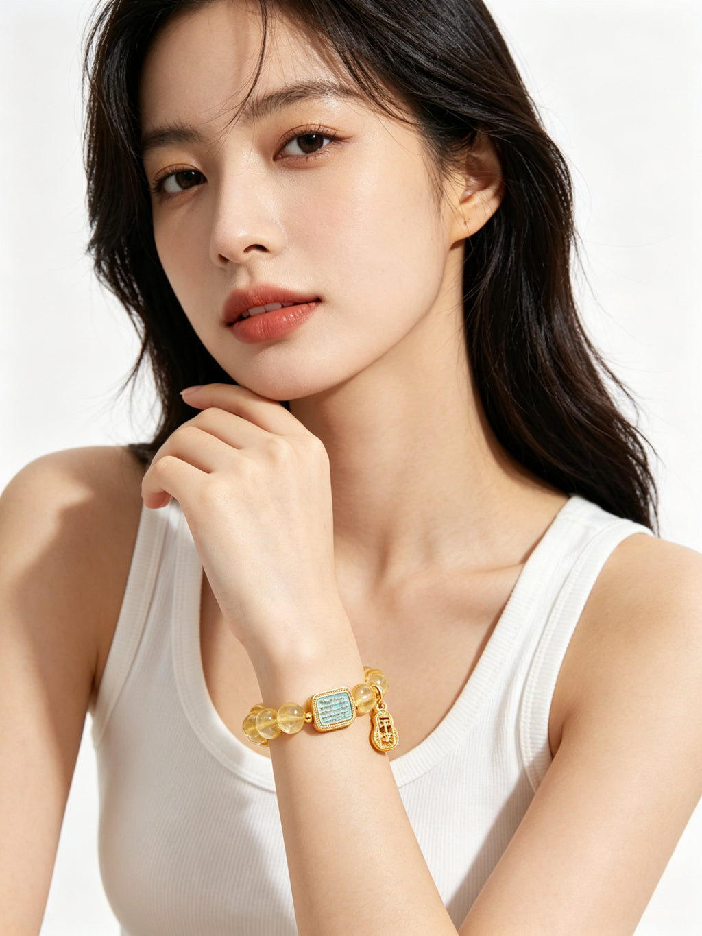 Close-up of hollow gold safe gourd "peace" pendant on metal element citrine bracelet, delicate vintage carving details against white background