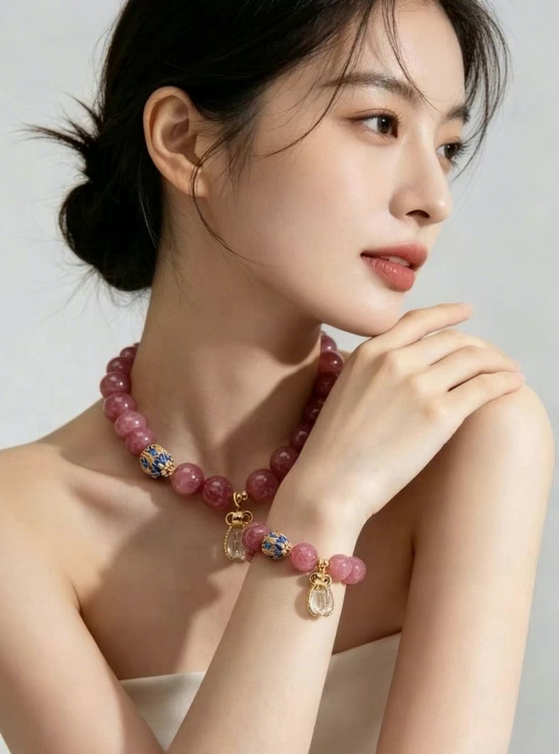 Slow close-up footage of female hand gently rotating wrist to display Fire Element pink tourmaline bracelet, fully show natural pink tourmaline beads, cloisonne ornaments and clear quartz pendant, soft neutral studio background, 3:4 vertical e-commerce product display video
