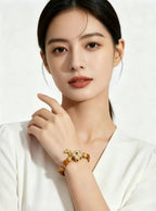 Vertical 3:4 slow motion footage showing Earth Element golden tiger's eye bracelet worn on female wrist, model in white clothes, plain white background oriental jewelry showcase