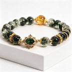 Close-up of golden rutilated quartz accent bead on wood element green phantom bracelet, contrast of green and warm gold stone tones, plain white background product photo