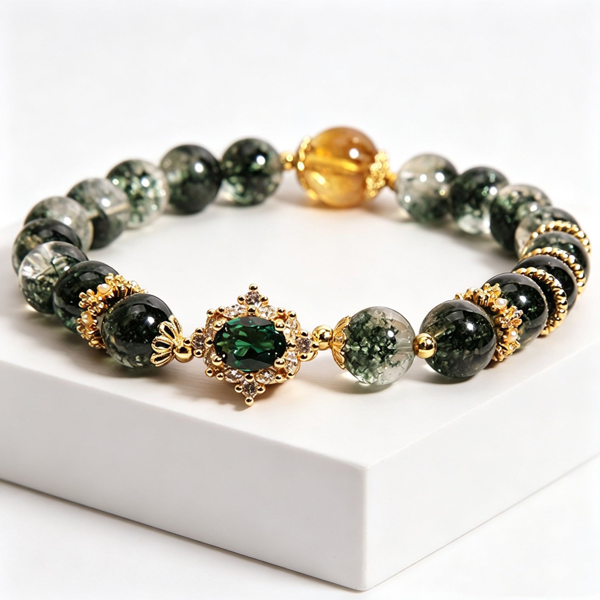 Close-up of golden rutilated quartz accent bead on wood element green phantom bracelet, contrast of green and warm gold stone tones, plain white background product photo